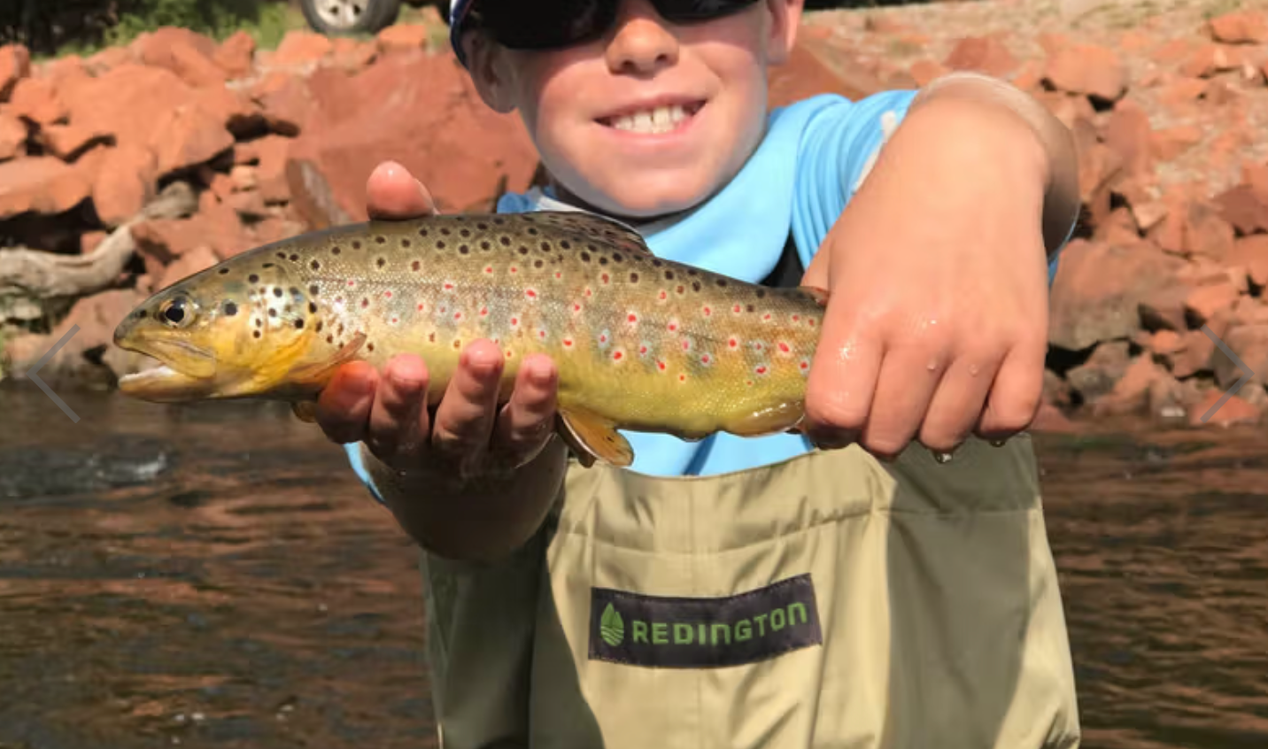 Child holding a fish with a Redington logo in the background
