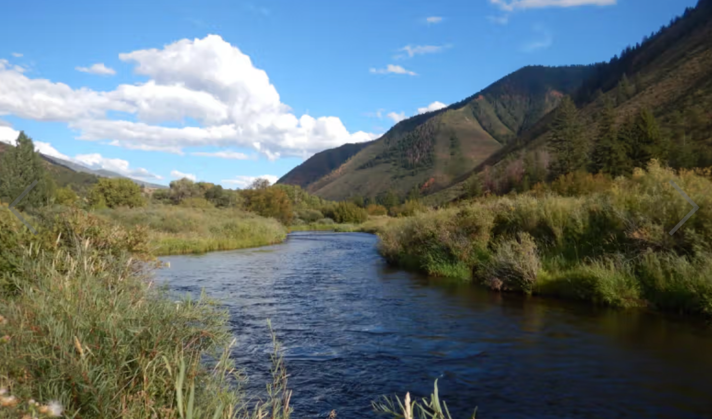 Stream running through a valley with mountains and blue sky