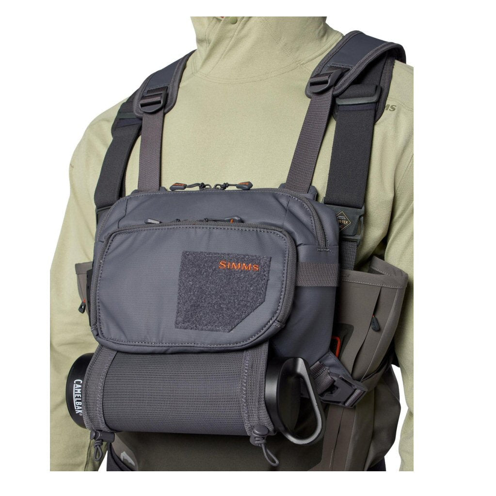 Simms Tributary Chest Pack worn over Simms wading jacket, showing fit, CamelBak bottle holder, and zippered compartments for fly fishing
